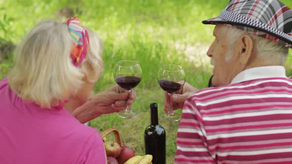 Family Weekend Picnic in Park. Active Senior Old Caucasian Couple Sit on Blanket and Drink Wine