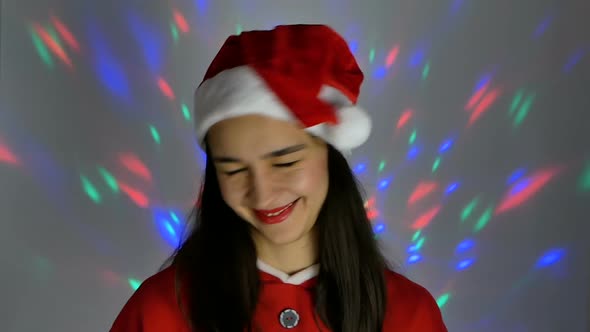 Pretty Young Woman in Santa Claus Hat Smiling and Looking Coquettishly at the Camera. New Year