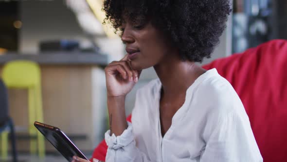 Happy african american woman sitting in cafe using digital tablet and smiling