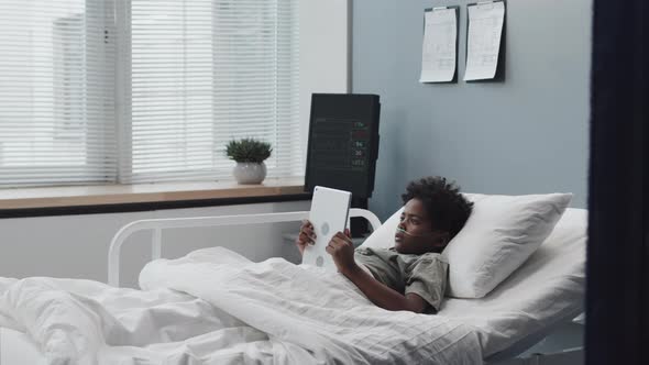 Black Boy Using Tablet in Hospital Bed