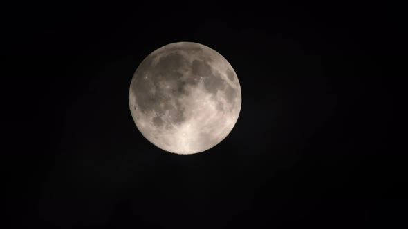 Clouds passing by the full moon, real time shot. Full moon at night with clouds in real time.