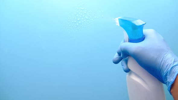 Hand in Blue Rubber Gloves Holding Spray Bottle with Copy Space 