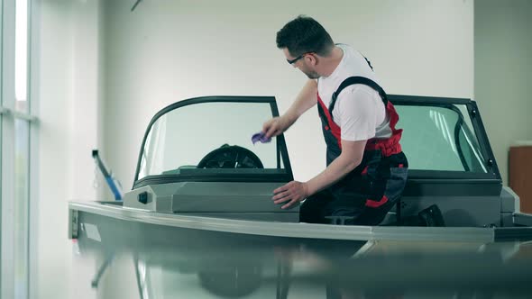 Male Technician Is Cleaning Windshield of a Sailboat