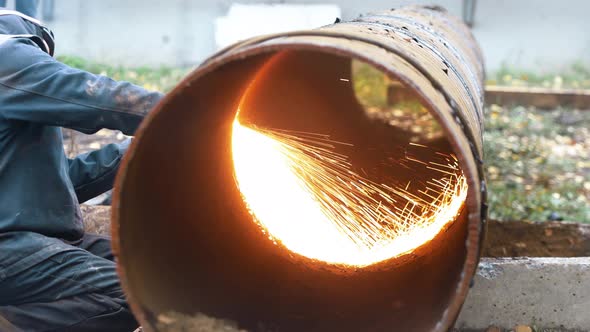 The Welder Cuts a Large Diameter Metal Pipe and Sparks Fly