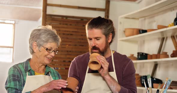 Male and female potter interacting while examining a pot