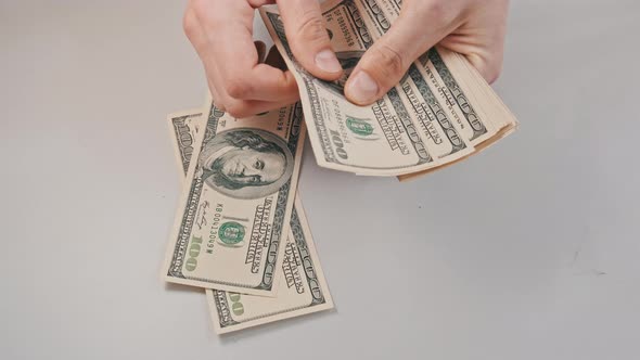 Male Hands Counting Old Hundred Dollar Banknotes on a White Table