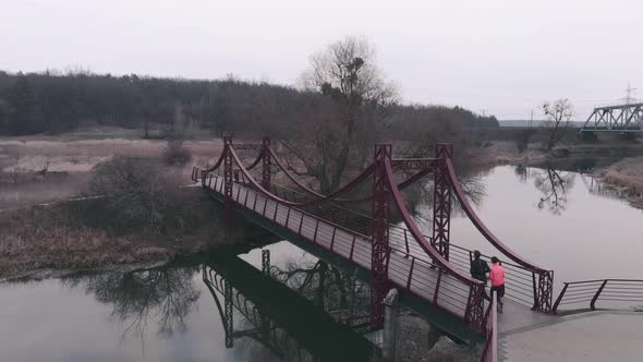 Sportive couple running on bridge, Man and woman jogging in park with river and bridge