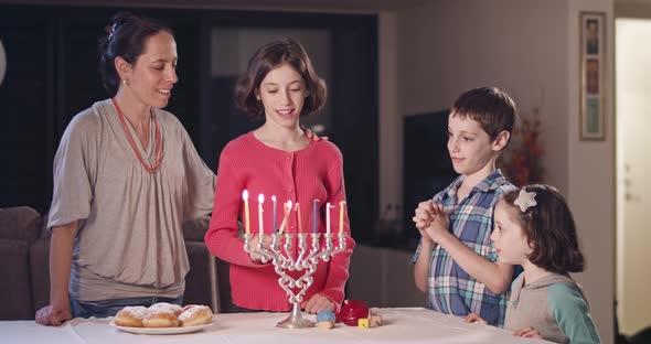 Kids and their mother lighting Hanukka candles