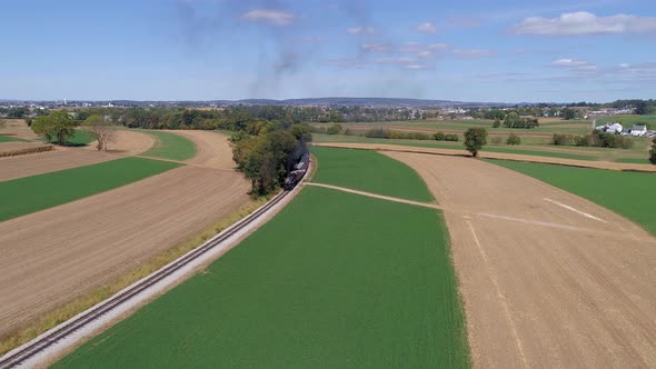 Aerial View of an Antique Steam Passenger Train travel along Farm Countryside