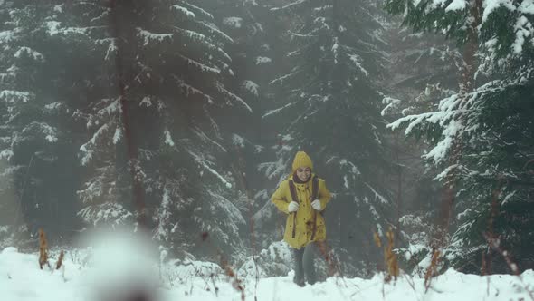Woman Walking Alone in Winter Forest Enjoying Wilderness Wearing Yellow Winter Clothes and Backpack