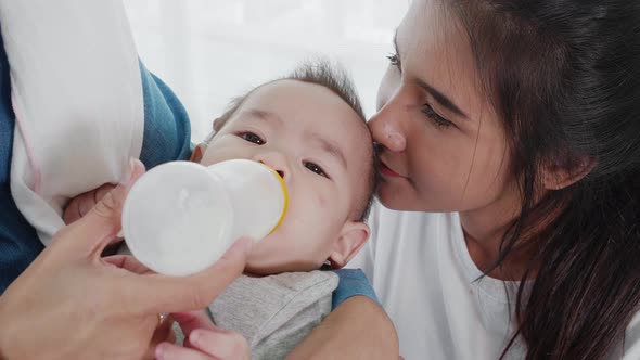 The baby drinks from a bottle of milk.