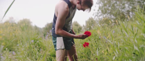 Man smells flower in field