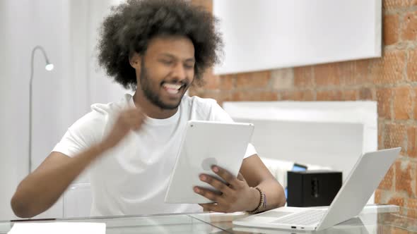 African Man Celebrating Success of Project on Tablet