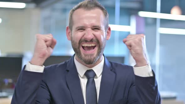 Portrait of Successful Businessman Celebrating with Both Fist