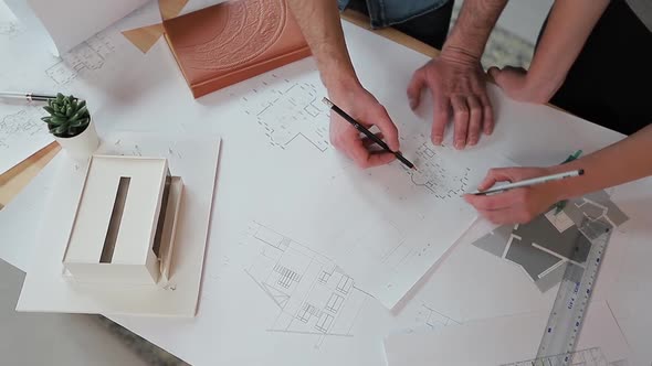 Close Up Hands of Two Workers Discussing Building Drawings in Office. Closeup Shooting of Arms