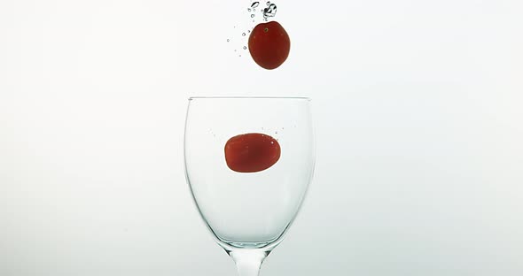 Cherry Tomatoes, solanum lycopersicum, Fruits falling into Water against White Background
