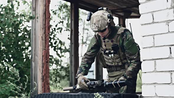 Military Man with Gun Case Takes Out an Assault Rifle in Destroyed City. Military and Rescue