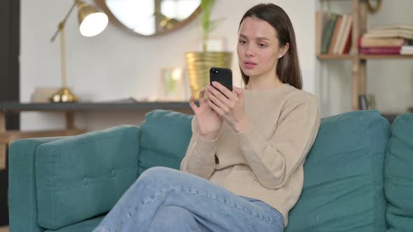 Young Woman Using Smartphone on Sofa