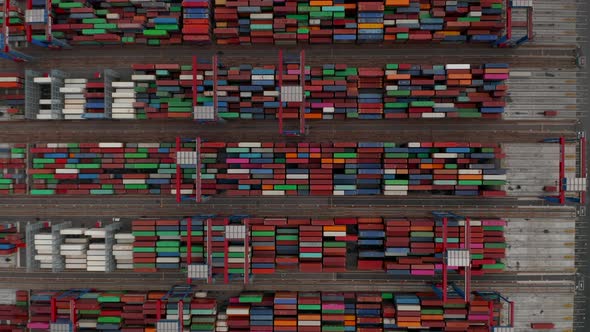 Top Down Birds Eye Aerial View of Industrial Cranes Moving Large Containers in Cargo Port