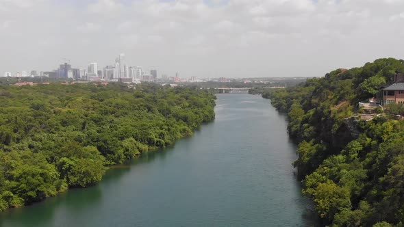 High drone shot of ladybird lake and the cliffs. Shows a home with the view of downtown Austin on th