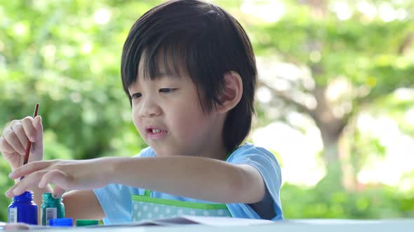 Cute Asian Child Enjoying Arts And Crafts Painting With His Hand