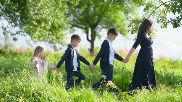 Happy Mom Hugs Beloved Children in the Summer Park