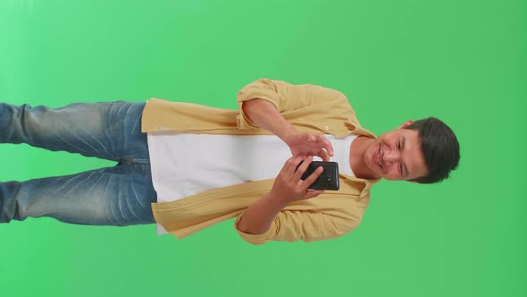 Young Asian Man Surprise And Say Wow During Use Mobile Phone In Green Screen Studio