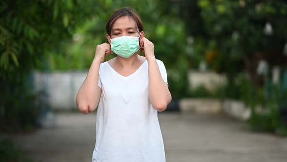 4K footage of A woman in a white T-shirt taking off a medical mask and smiling.