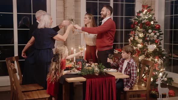 Whole Family Gets Up From the Table to Have a Glass on Christmas Eve Smiling