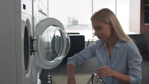 Woman Loading Dirty Clothes In Washing Machine In Kitchen