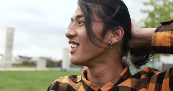 Young asian man posing in front of camera at city park