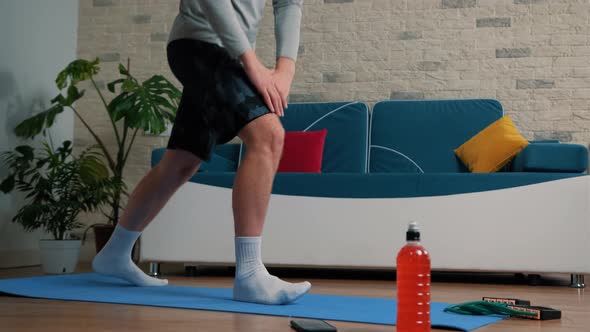 Young Man Doing Sport Exercises at Home on a Blue Mat