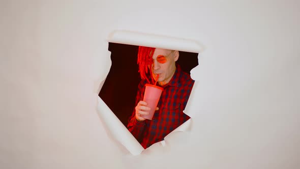 Young Man in Red Plaid Shirt Drinking Through Soft Drink Straw in Hole of White Background