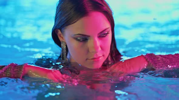 Glamorous Sexy Woman in Pool Water Under Neon Color Light