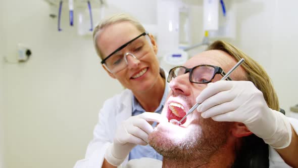 Female dentist examining male patient with tools