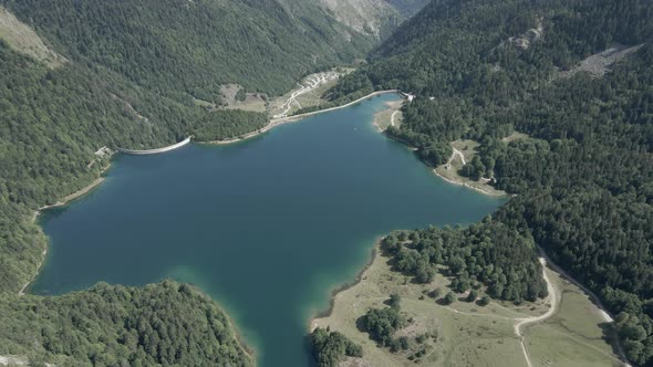 Aerial View Forwarding Shot Over the Ayous Lake Surrounded By Lush Green Vegetation on All Sides in