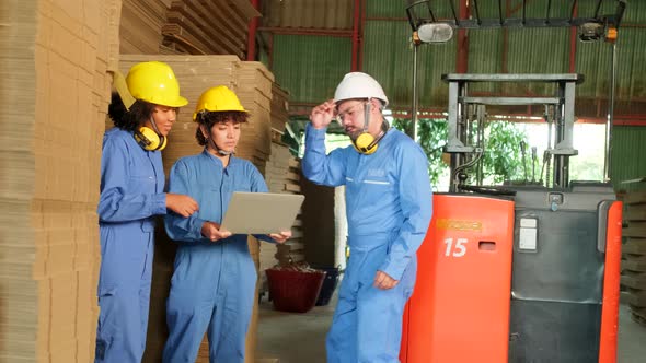 Workers team inspect stock at factory warehouse, management piles of  cardboard.