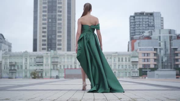 Back View of Beautiful Gorgeous Girl in a Stunning Evening Green Dress Walking Fascinatingly on