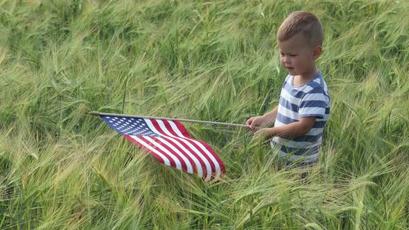 Baby Boy Waving American Flag in Wheat Rye Field in Sunny Day Independence Day
