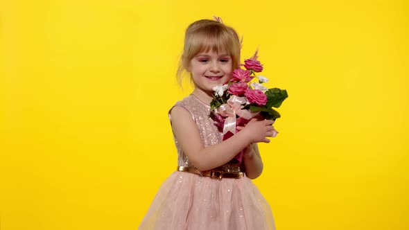Little Child Girl with Fashion Makeup Standing with Bouquet of Flowers Isolated on Yellow Background