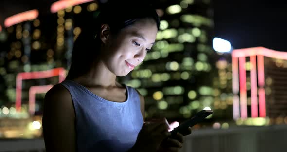 Woman use of mobile phone in city at night 