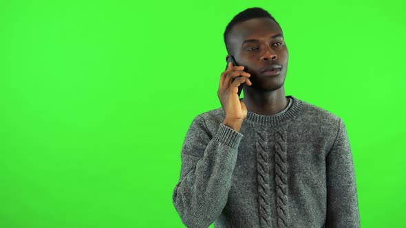 A Young Black Man Talks on a Smartphone - Green Screen Studio