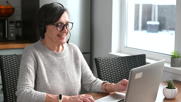 Cheerful Mature Woman Using a Laptop for Remote Work From the Home Office