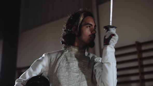 Young Man Pointing Fencing Foil and Putting on Mask