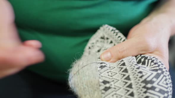 Female Hands Sew a Piece of Fabric to a Knitted Product with a Thread and a Needle