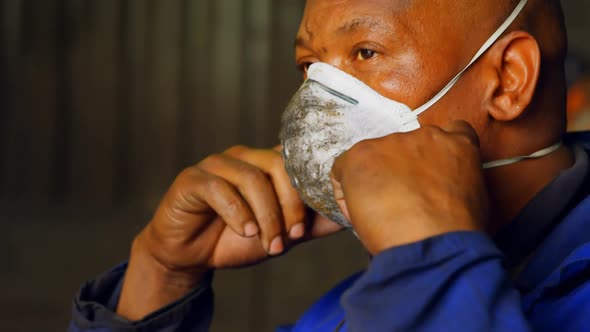 Worker removing mask in foundry workshop 4k