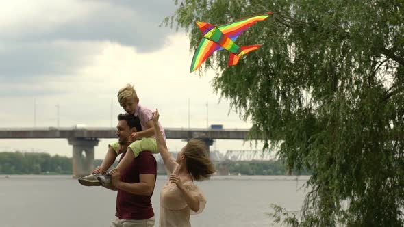 Mother Flying Kite Together With Son Sitting on Fathers Shoulders, Happiness