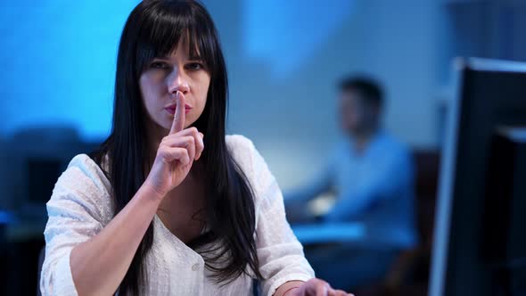 Concentrated Woman Typing on Keyboard and Showing Hush Gesture Finger on Lips