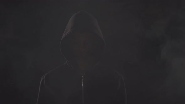 Portrait of computer hacker in hoodie. Obscured dark face.