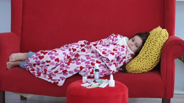 Sick Girl Resting on Red Couch in Living Room